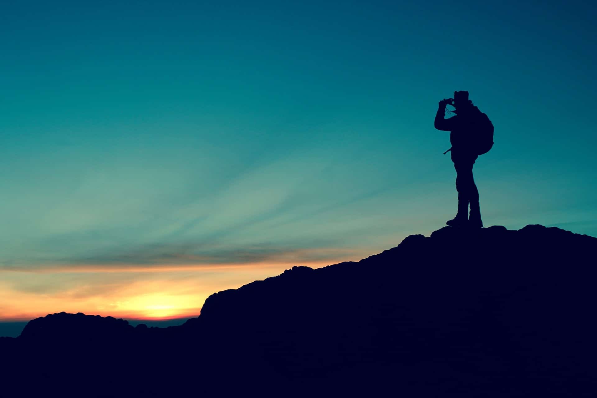 A man on top of mountain with binoculars on