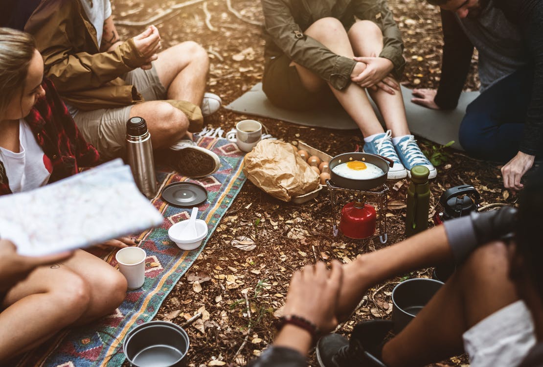 campers sharing a meal while seated on the ground
