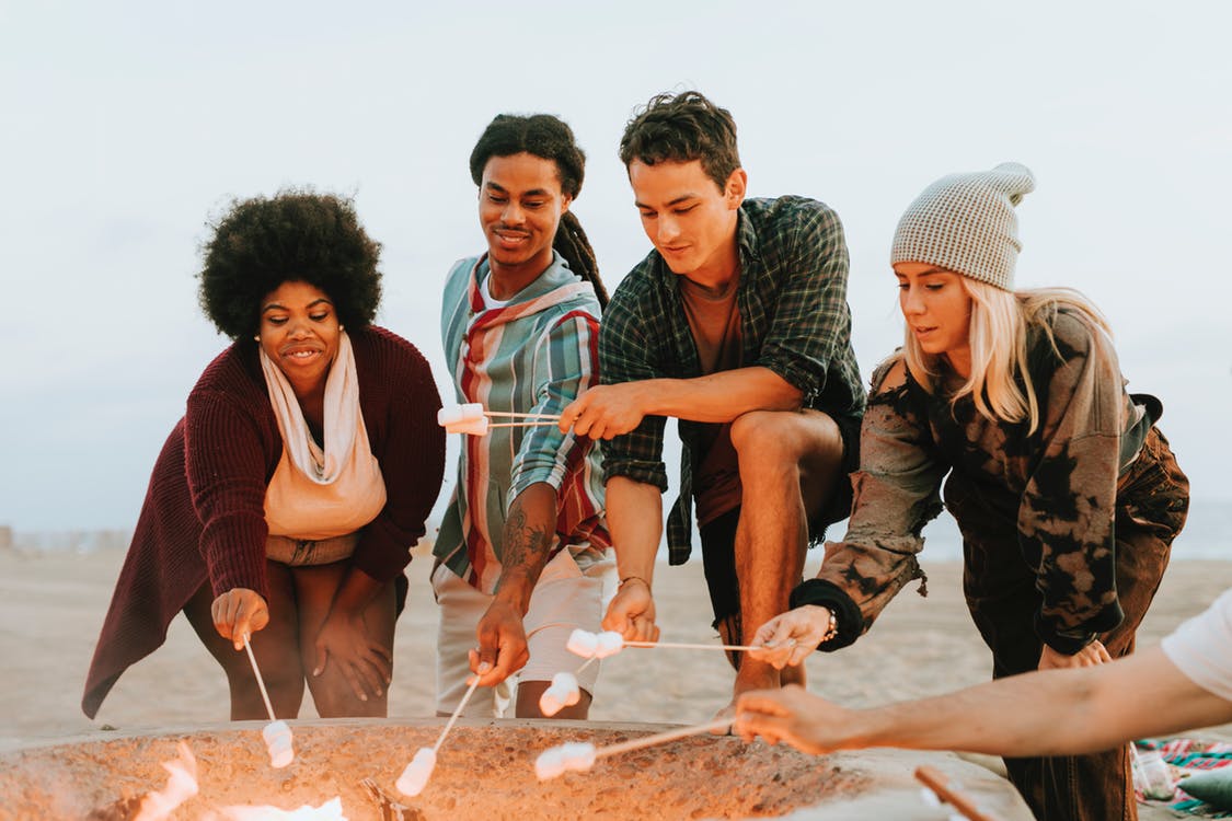 four people toasting marshmallows on the bonfire