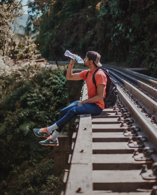 man sitting on the rails drinking water