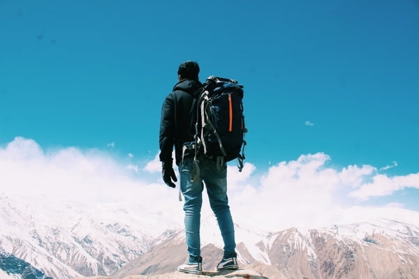 guy standing on top of the mountain with hiking backpack
